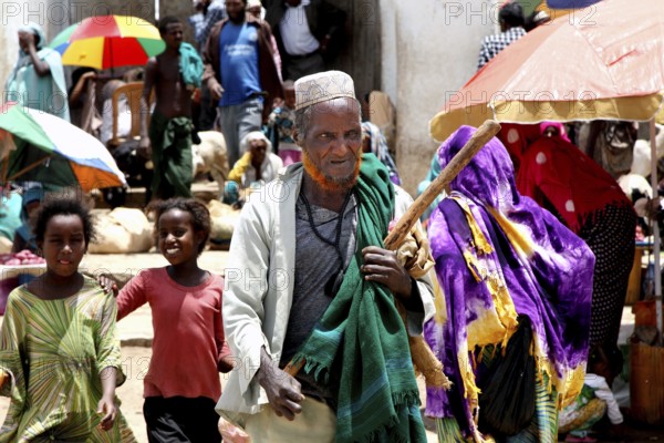 Lively market in Harar with people wearing traditional robes and colorful umbrellas, Harar, Oromia, Ethiopia