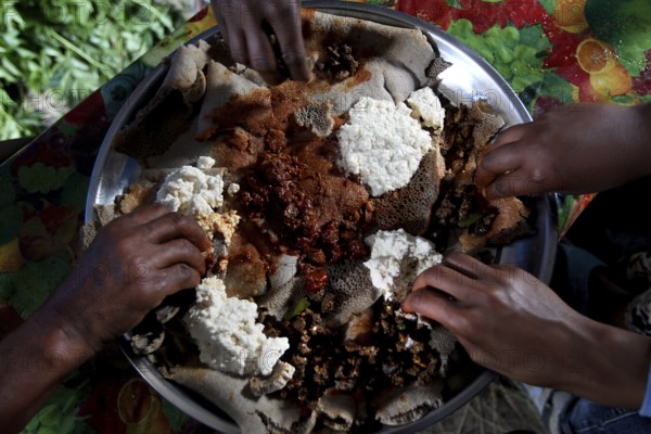 Eating together on a large food platter with Injera with Chuchu's family in Lalibela, Lalibela, Amhara, Ethiopia