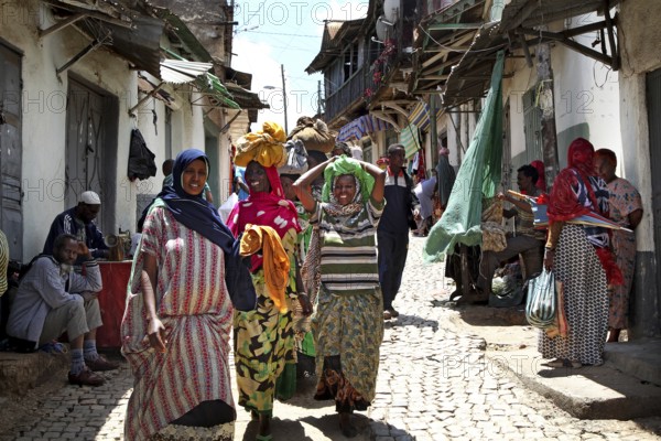 Women wearing traditional clothes stroll through a busy alley in Harar, Harar, Oromia, Ethiopia