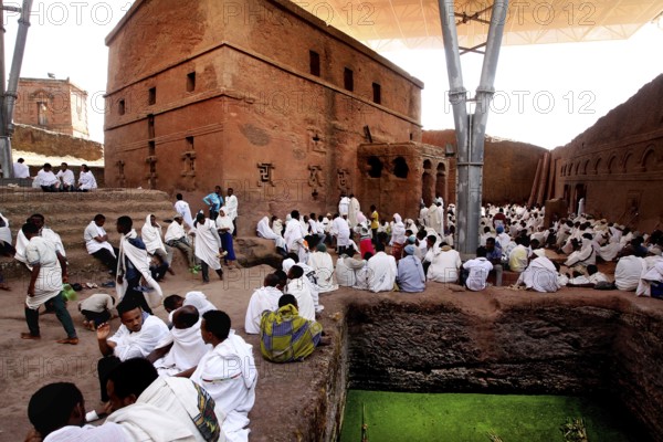People wearing white clothes gather in front of the Bete Maryam rock church, Lalibela, Amhara, Ethiopia