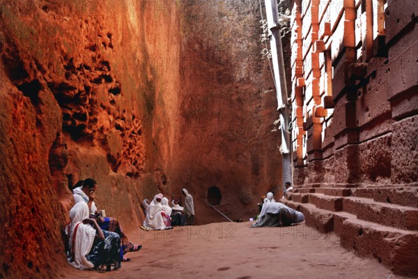 People wearing traditional clothing sit at Bete Emanuel, impressive rock architecture, Lalibela, Amhara, Ethiopia