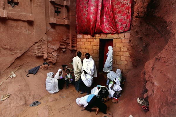 Believers gather in front of the Bete Abba Libanos church under a red cloth, Lalibela, Amhara, Ethiopia
