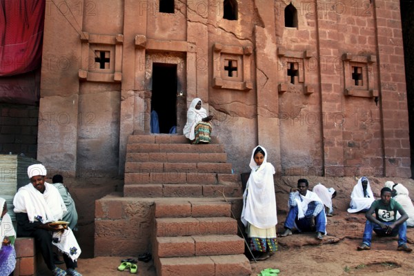 People wearing traditional dress in front of the rock church of Bete Abba Libanos in Lalibela, Lalibela, Amhara, Ethiopia