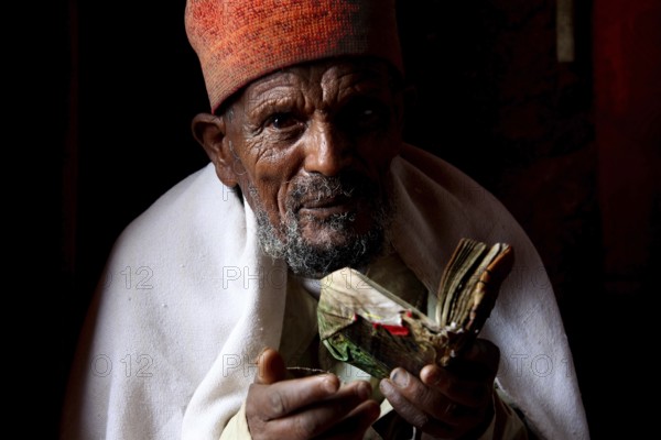 Man holding a book in a reverent position in Bete Abba Libanos, Lalibela, Ethiopia