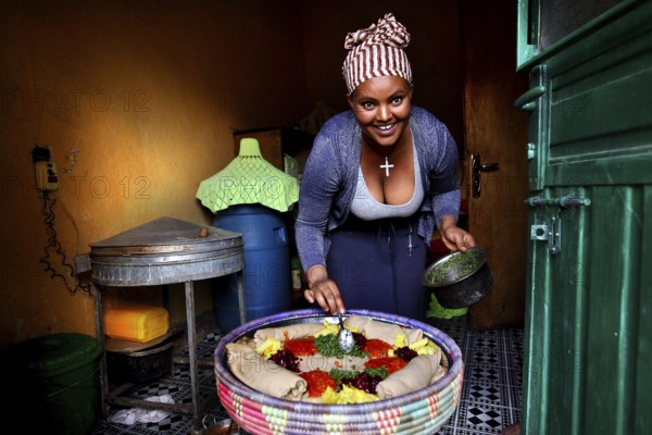 Worknesh serves food in a traditionally decorated kitchen, Lalibela, Ethiopia
