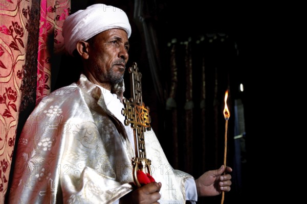 Priest with an ornate cross celebrates a ceremony in the Bete Meskel church. Expression of dedication, Lalibela, Amhara, Ethiopia