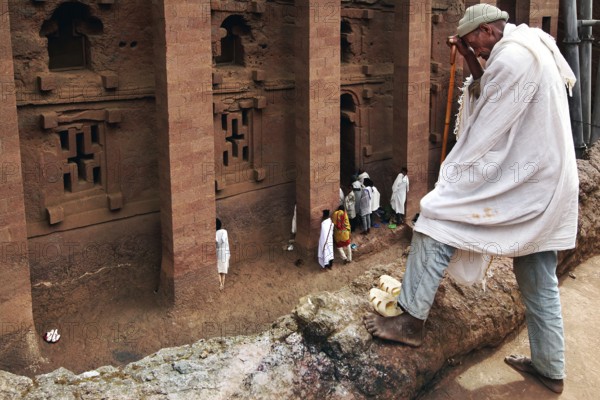 Pilgrim enters the imposing rock church of Bete Medhane Alem in Lalibela. The scene appears calm and contemplative, Lalibela, Amhara, Ethiopia