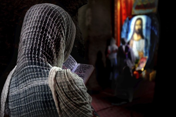 Person in church deepening in prayer in front of religious icons, Lalibela, Amhara, Ethiopia