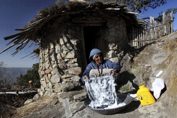 Woman washing in front of a traditional round hut with picturesque views of Lasta Mountains, Lalibela, Amhara, Ethiopia