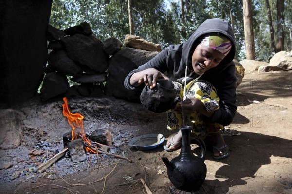 Woman prepares traditional coffee in the Lasta Mountains. The atmosphere is warm and inviting, Lalibela, Amhara, Ethiopia