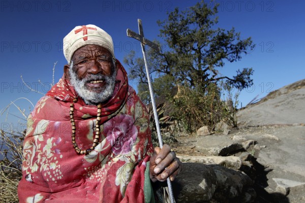 Priest with colorful blanket and cane in mountainous landscape, Lalibela, Lasta Mountains, Ethiopia