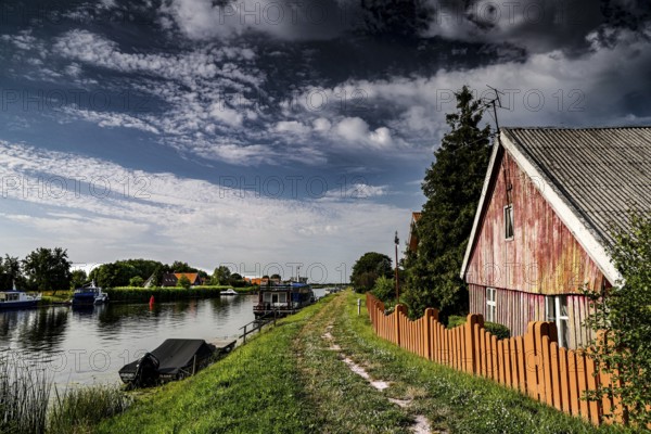 Wooden house on the riverbank in a rural river landscape, Minge, LT