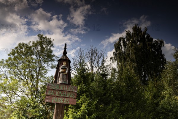 Entrance sign with carved figure in front of trees in Zemaitija National Park, Zemaitija National Park, Telšiai County, Lithuania