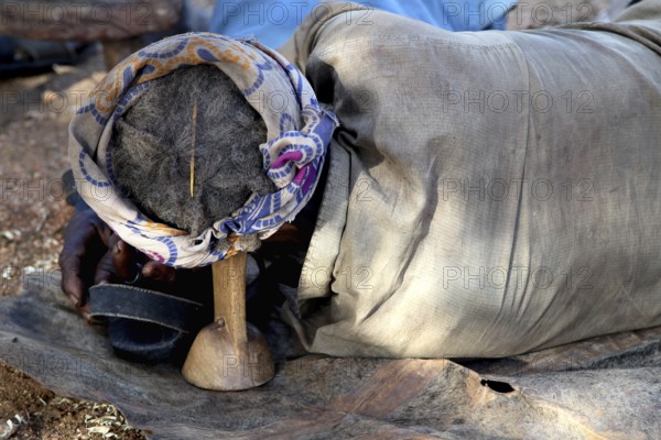 Hamer-Mann sleeps relaxed on traditional Berkota support, Turmi, null, Ethiopia