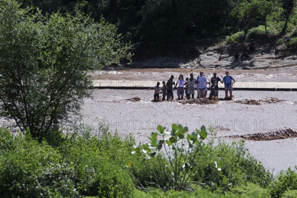 Tourists look at a river surrounded by green trees, Turmi, Ethiopia