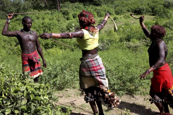 In the midst of lush nature, Hamer woman perform a whipping as part of a traditional initiation ritual, Turmi, Ethiopia