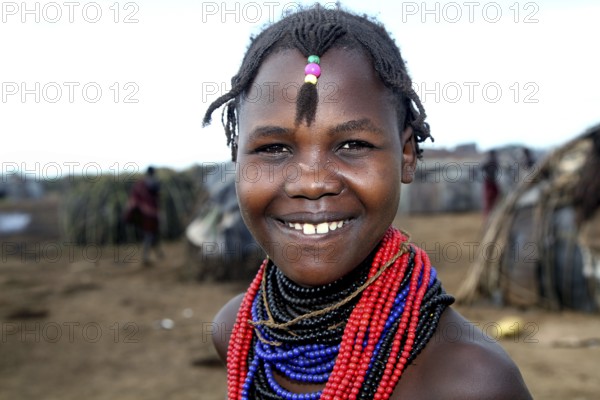 Young woman with colorful necklaces smiles in a Dessanech village, Omorate, Ethiopia