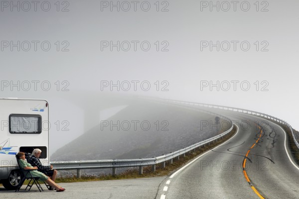Camper sitting on the side of the road on the foggy Atlantic road with steeply rising asphalt, Lauvøyford, Norway