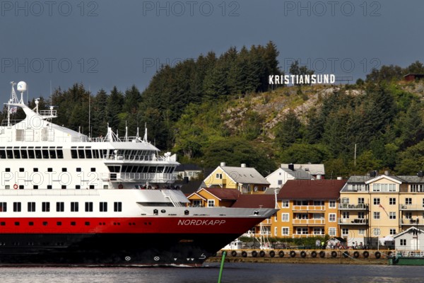 Hurtigruten ship off the coast of Kristiansund with colorful houses and forest, Kristiansund, Møre og Romsdal, Norway
