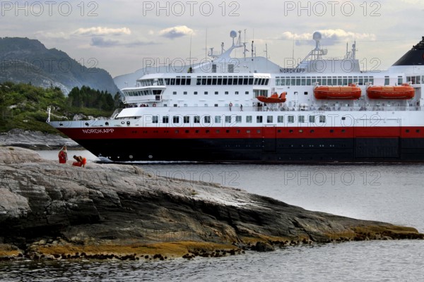 Hurtigruten ship near rocks and mountains on open sea, Kristiansund, Møre og Romsdal, Norway