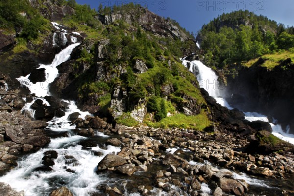 Låtefossen Waterfall flows powerfully over rocky landscape, surrounded by green nature, zero