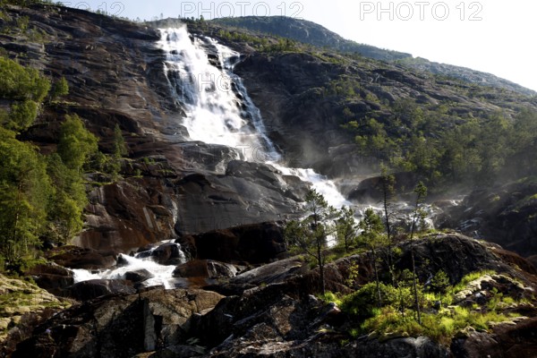 Majestic waterfall falls over rocks amidst green vegetation, Langfossen, Norway