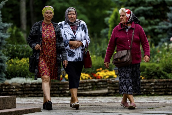 Three woman wearing headscarves stroll through the garden in Kuremäe, Kuremäe, Pühtitsa, Estonia