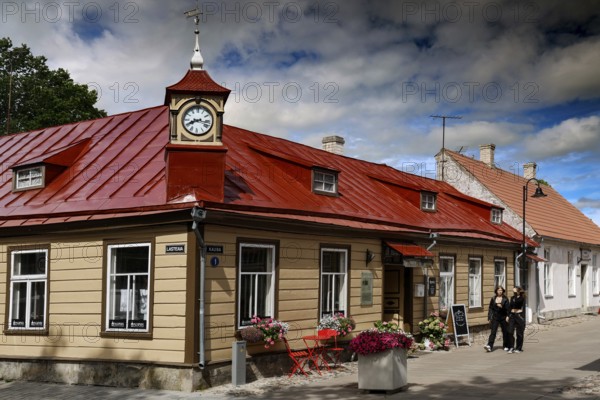 Historic building with red roof in the old town, people walking along the street, Kuressaare, Saaremaa, Estonia