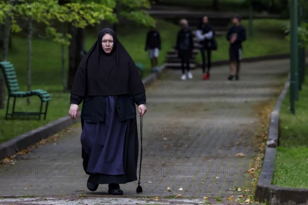 Nun with walking stick walks through the park in Kuremäe, Kuremäe, Pühtitsa, Estonia