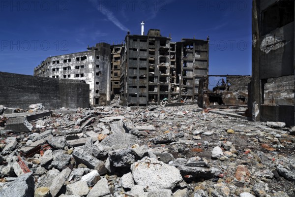 Abandoned ruins of Gunkanjima with crumbling buildings and debris under clear skies, Nagasaki, Japan