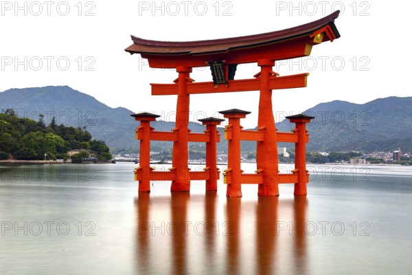 Red torii of Itsukushima Shrine stands in calm water, Miyajima, Japan