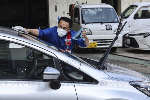 A gas station attendant in Nagasaki cleans the windshield of a car, Nagasaki, Nagasaki, Japan