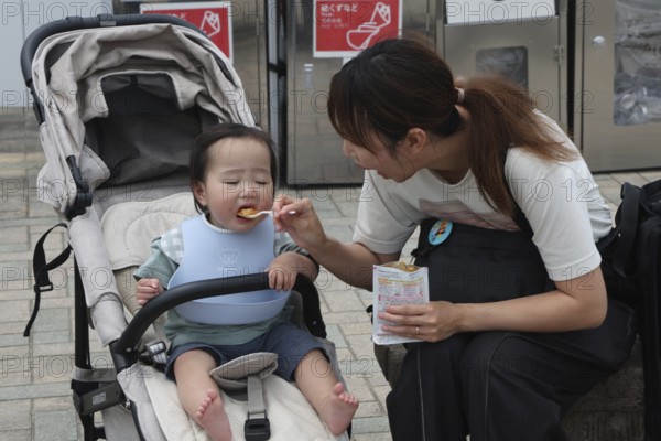 A mother feeds her child at a rest stop in Nagasaki, Nagasaki, Japan