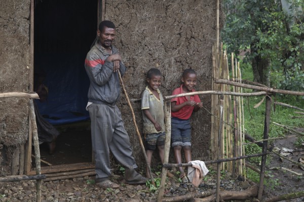 Man with two children in front of a traditional house along the route from Yirga Alem to Yabello, Yirga Alem, Yabello, Ethiopia