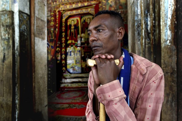 Believer is leaning on a stick at Ura Kidhane Mihret Church on Lake Tana, Lake Tana, Ethiopia