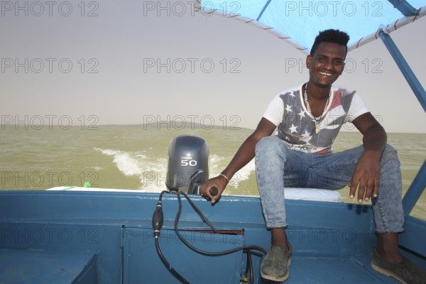 Captain rides a motor boat on Lake Tana under a blue sky, Lake Tana, Ethiopia