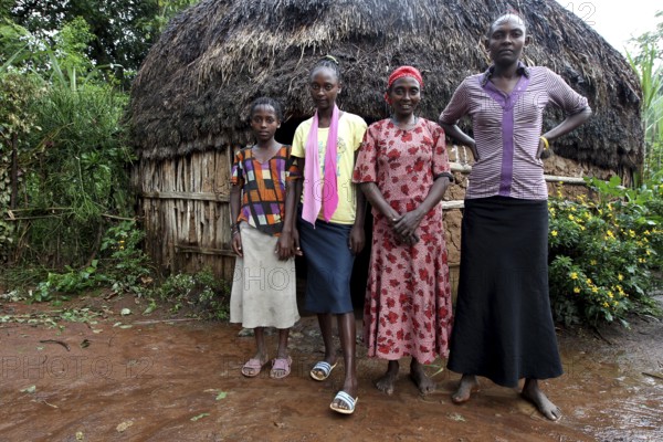 Wife and three daughters pose together in front of a traditional hut, Yirga Alem, Ethiopia