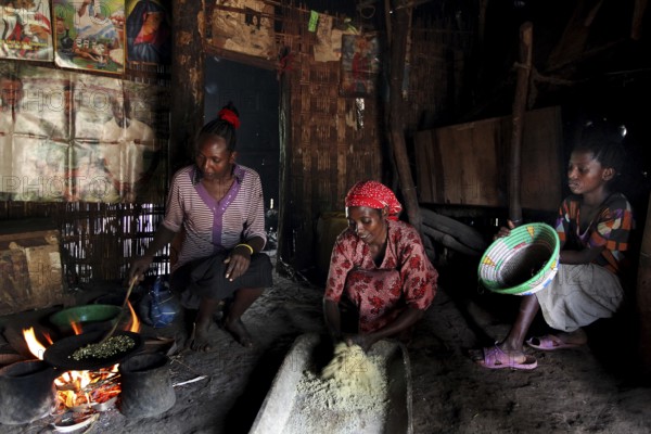 Women in a hut preparing food traditionally with mortar and pestle, Yirga Alem, Ethiopia