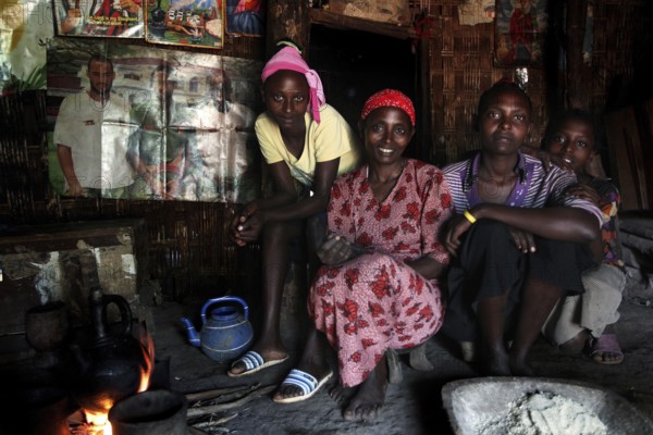 Woman with her daughters in a hut sitting together at a fireplace, Yirga Alem, Ethiopia
