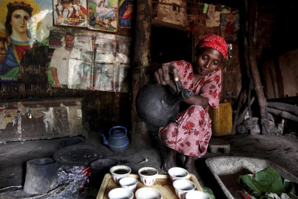 Woman performs a traditional coffee ceremony in a decorated hut, Yirga Alem, Ethiopia