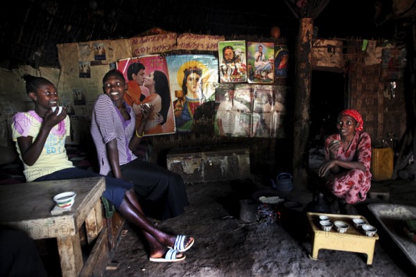 Women sitting in a cozy hut laughing and enjoying time together, Yirga Alem, Ethiopia