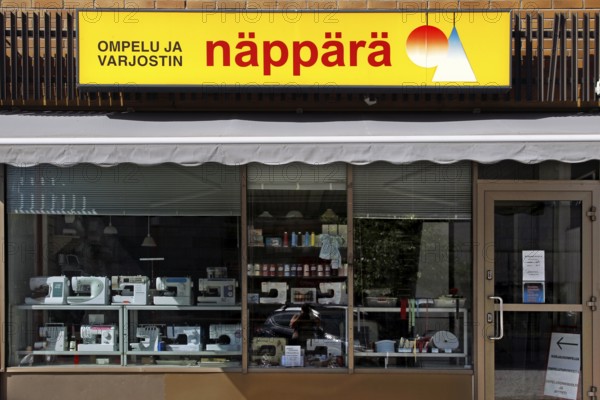 Shop front with yellow Näppärä sign and shop window of a textile shop, Rovaniemi, Finland
