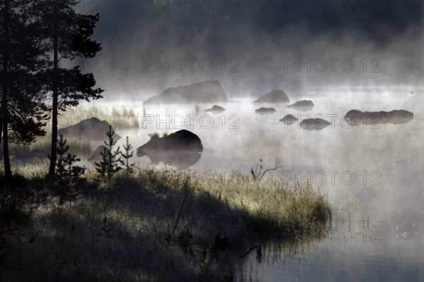 Misty lake landscape in Lapland surrounded by stones and trees, Lapland, Finland
