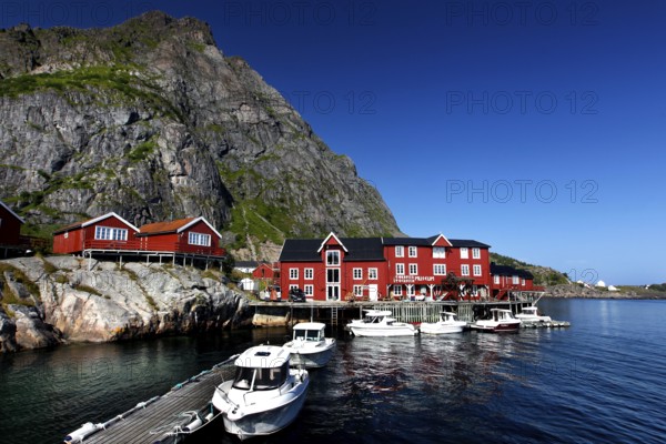 Red houses and boats in the harbor of Å in front of impressive rock, Å, Moskenesøy, Norway