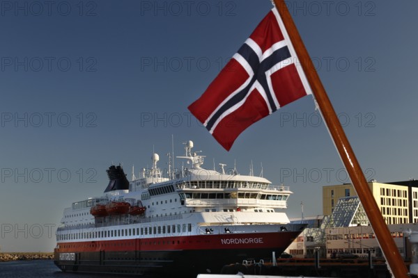 Hurtigruten ship with Norwegian flag in Svolvær harbour, clear visibility and blue sky, Svolvær, Nordland, Norway