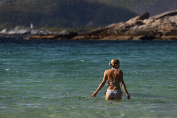 Woman bathing in clear blue water on Rårvik beach in Lofoten, Austvågøy, Lofoten, Norway