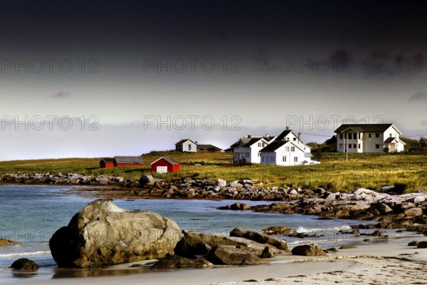 Small settlement with white houses on the beach, surrounded by rocks and sea, Ramberg, Flakstadøy, Norway