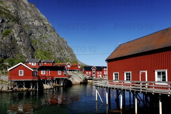 Red fishermen's houses in Sakrisøy against the majestic Lofoten mountains, Sakrisøy, Moskenesøy, Norway
