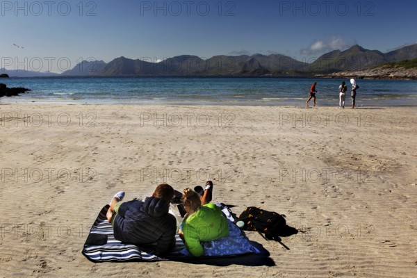 Relaxed beach atmosphere on Austvågøy with calm sea and sunbathing people, Lofoten, Nordland, Norway