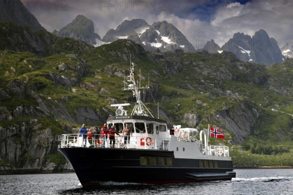 Tourists enjoy a boat trip in Trollfjord with mountain backdrop, Austvågøy, Raftsund, Norway